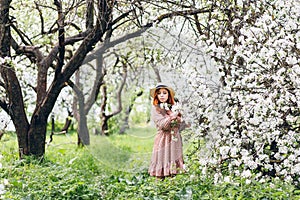 Red-haired girl walks in a spring blooming apple orchard