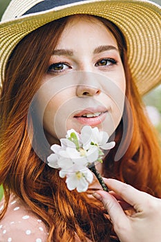 Red-haired girl walks in a spring blooming apple orchard