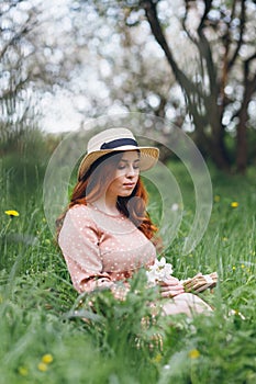 Red-haired girl walks in a spring blooming apple orchard