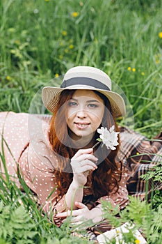 Red-haired girl walks in a spring blooming apple orchard