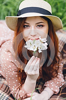 Red-haired girl walks in a spring blooming apple orchard