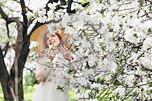 Red-haired girl walks in a spring blooming apple orchard