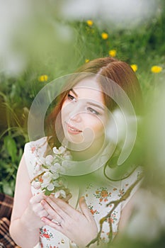 Red-haired girl walks in a spring blooming apple orchard