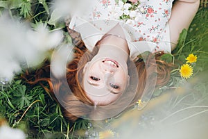 Red-haired girl walks in a spring blooming apple orchard