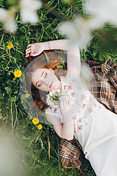 Red-haired girl walks in a spring blooming apple orchard