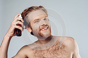 Red haired hairy man sprinkles balm on hair