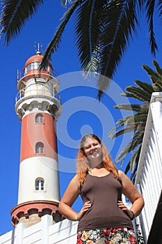 Red-haired happy white Caucasian girl stands next to the lighthouses in Swakopmund Namibia and cheerfully smiles