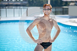 Red-haired man in sunglasses standing near pool