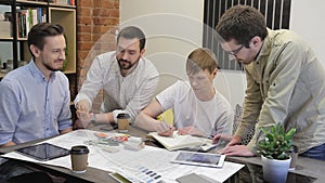 Red-haired man wrote in pencil on a sheet, and the other three look.