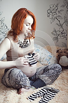 Red-haired pregnant woman in high-heeled shoes and fashionable personal clothes