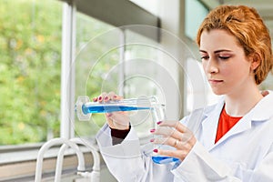 Red-haired scientist pouring liquid