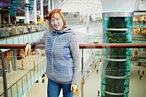 Red-haired smiling woman stands leaning at railing photo