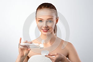 Red-Haired Teen Girl Applying Lotion On Cotton Pad, Gray Background