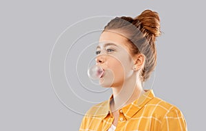 Red haired teenage girl blowing bubble gum