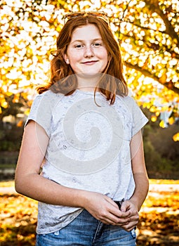 Red haired teenager standing under Autumn trees