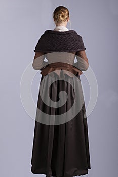 18th century woman in brown outfit on plain studio backdrop