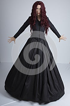 Red-haired woman in Black Victorian ensemble and a witch-like pose