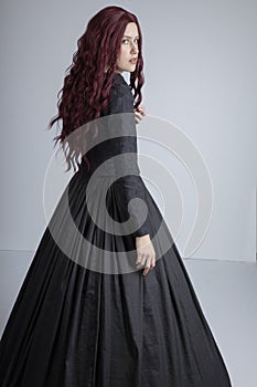 Red-haired woman in Black Victorian ensemble and a witch-like pose