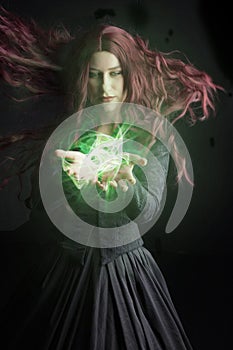 Red-haired woman in a black Victorian ensemble and a witch-like pose. An orb of light is in her hand.