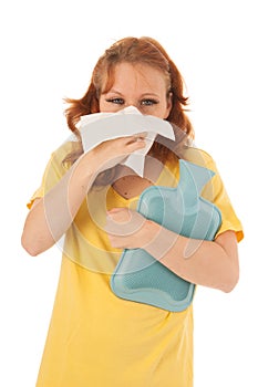 Red haired woman blowing nose with hot water-bottle