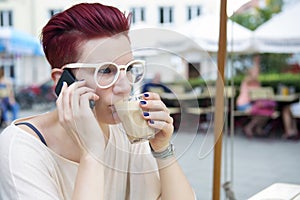 Red-haired woman drinking coffee and talking on the phone