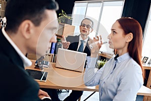 Red-haired woman is drinking glass of water, sitting next to adult man in divorce lawyer`s office.