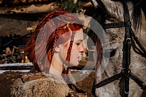 Red-haired woman with a faithful horse preparing for battle