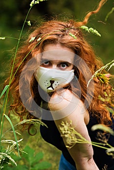 Red-haired woman in a mask with a cat`s face