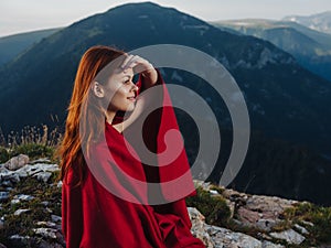 red-haired woman with a plaid on her shoulders are resting in the mountains photo