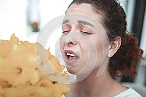 Red-haired woman with ponytail sneezing after smelling flowers