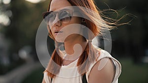 Red haired woman riding bicycle in city park on sunny day