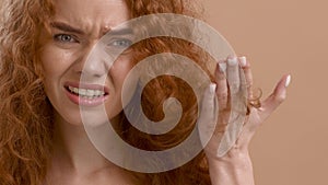 Red-Haired Woman Showing Damaged Hair And Split Ends, Beige Background