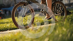 Red haired woman sitting on bicycle lying on grass in city park. Woman bike park