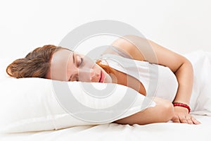 Red-haired woman sleeping on white pillow in bed at home