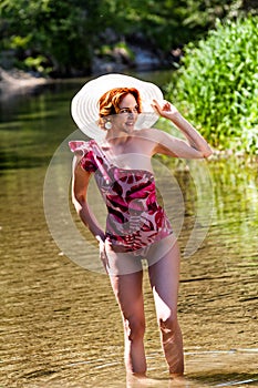 Red-haired woman standing in water on the beach