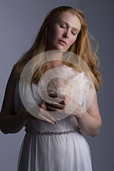 A red-haired woman wearing a diaphanous white gown and holding a feather