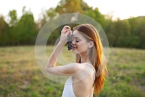 red-haired woman in a white dress in a field with grapes