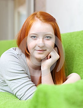 Red haired young girl relaxing on couch