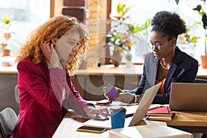 Red-haired young interior designer cooperating with colleague