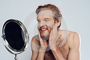 Red haired young man stroking beard
