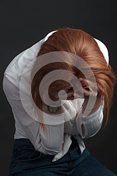 Red-haired young woman with freckles. He squeezes his head with his hands. Is in a stressful situation