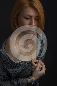 Red-haired young woman with freckles, in an unbuttoned shirt with bare shoulder