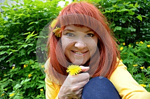 red-haired young woman girl with freckles with dandelion flower