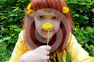 Red-haired young woman girl with freckles with dandelion flower