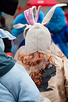 red hairs girl with rabbit costume parading in the street on back view