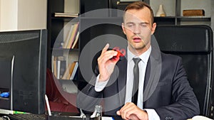 Red hand spinner, or fidgeting spinner, rotating on man`s hand. Man in a suit spinning a fidget spinner in his office at