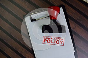 Red Handle Rubber Stamper and Cancellation Policy text isolated on wooden table