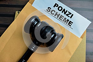 Red Handle Rubber Stamper and Ponzi Scheme text above brown envelope isolated on wooden background
