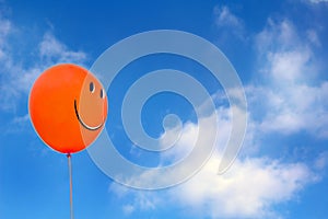 Red happy face balloon with blue sky athe background