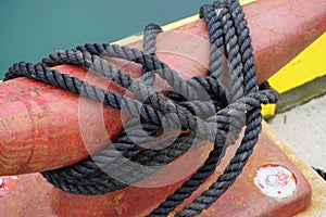 Red harbor cleat wrapped in black knotted rope photo